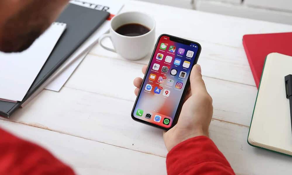 person holding a phone at a desk with a cup of coffee app development