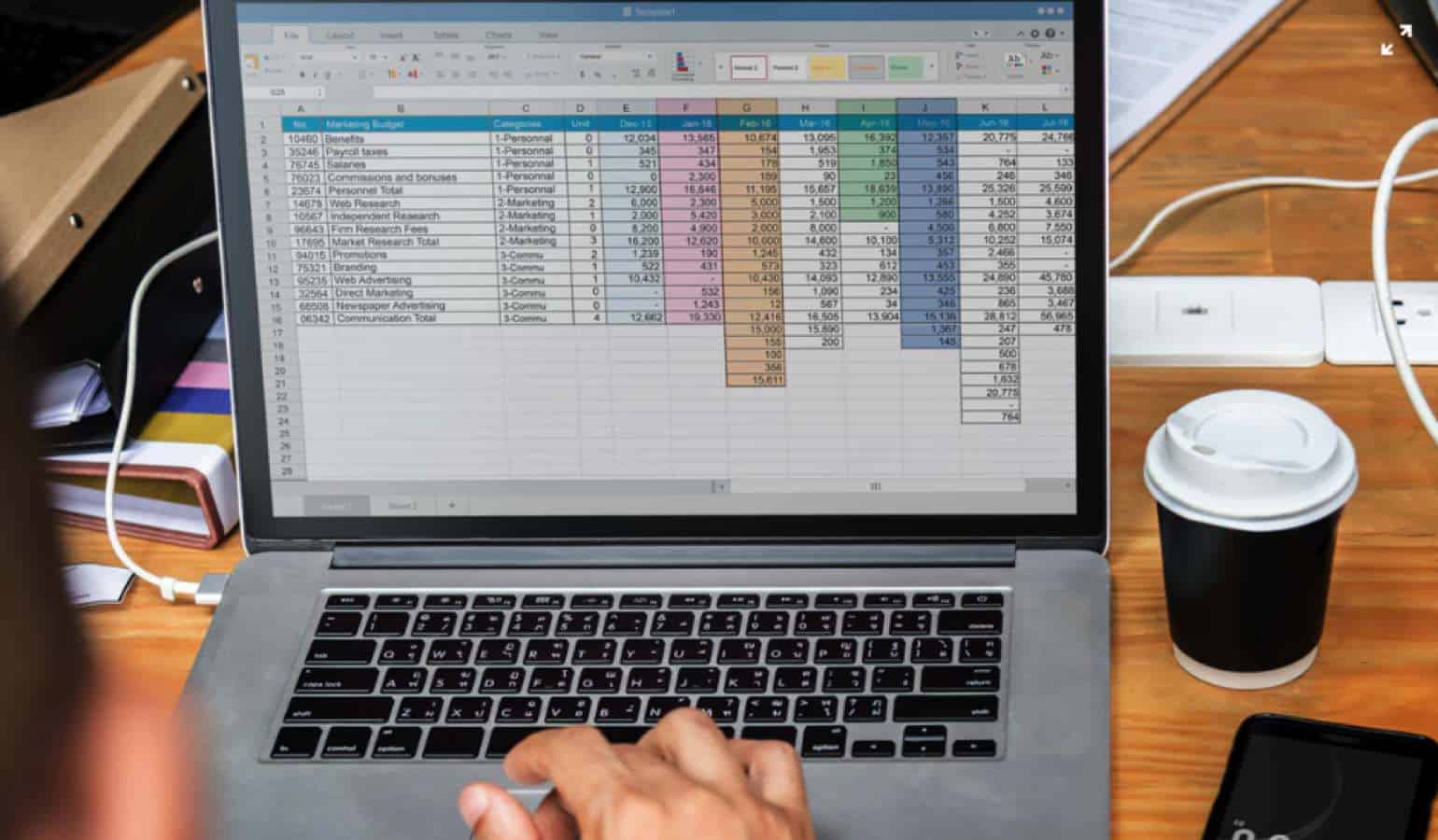 Laptop with microsoft excel open on a desk with cup of coffee