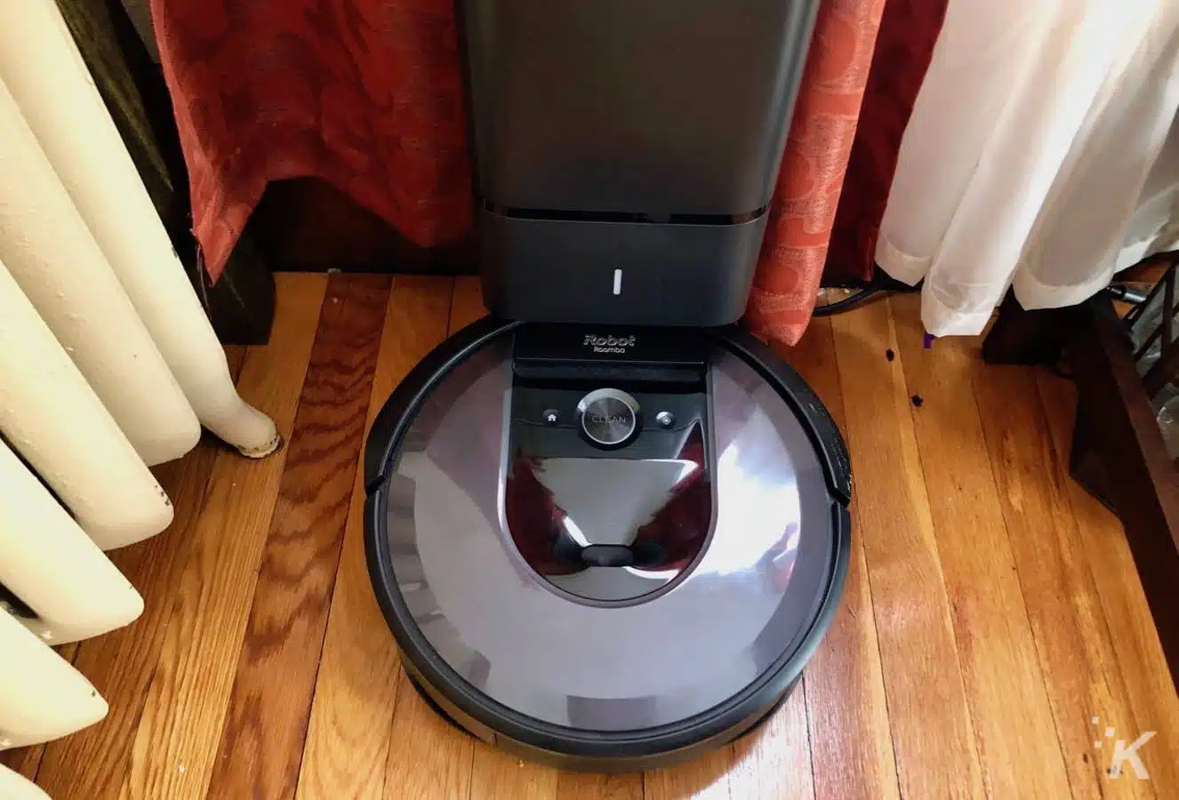 irobot roomba i7+ sitting on charger clean base hardwood floors