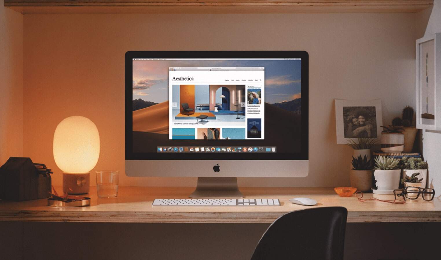 Imac setting on table surrounded by other desk items and lamp