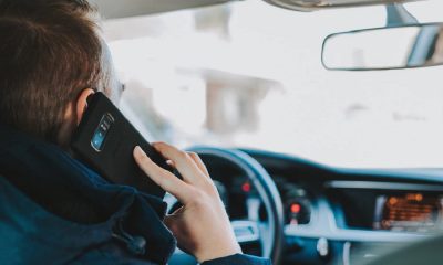 distracted driver on cell phone in car driving down road