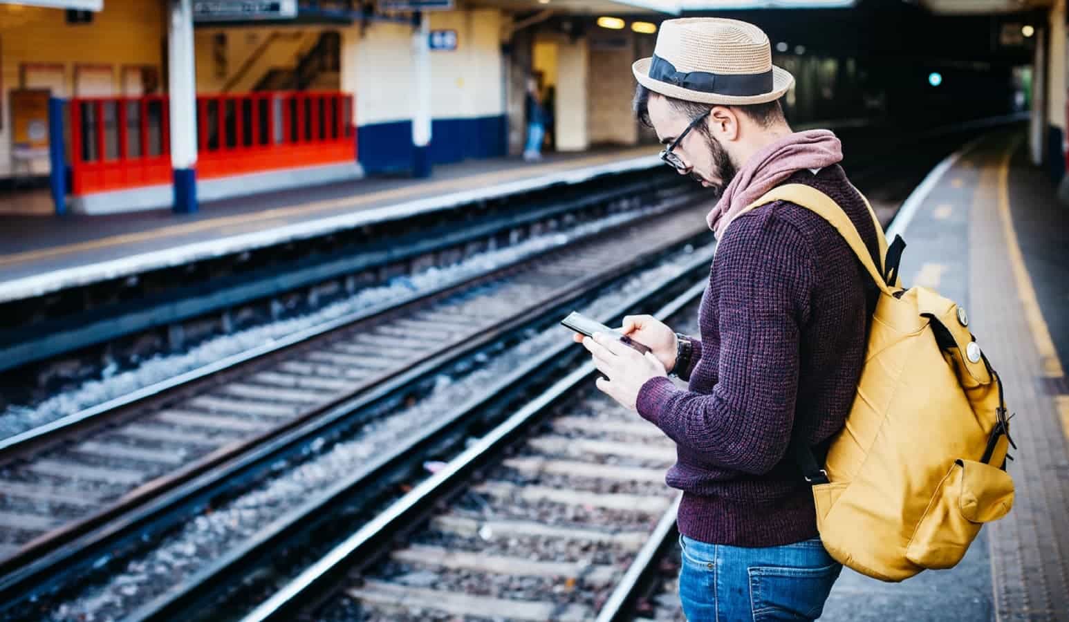 Person on phone playing a machine learning game near train tracks