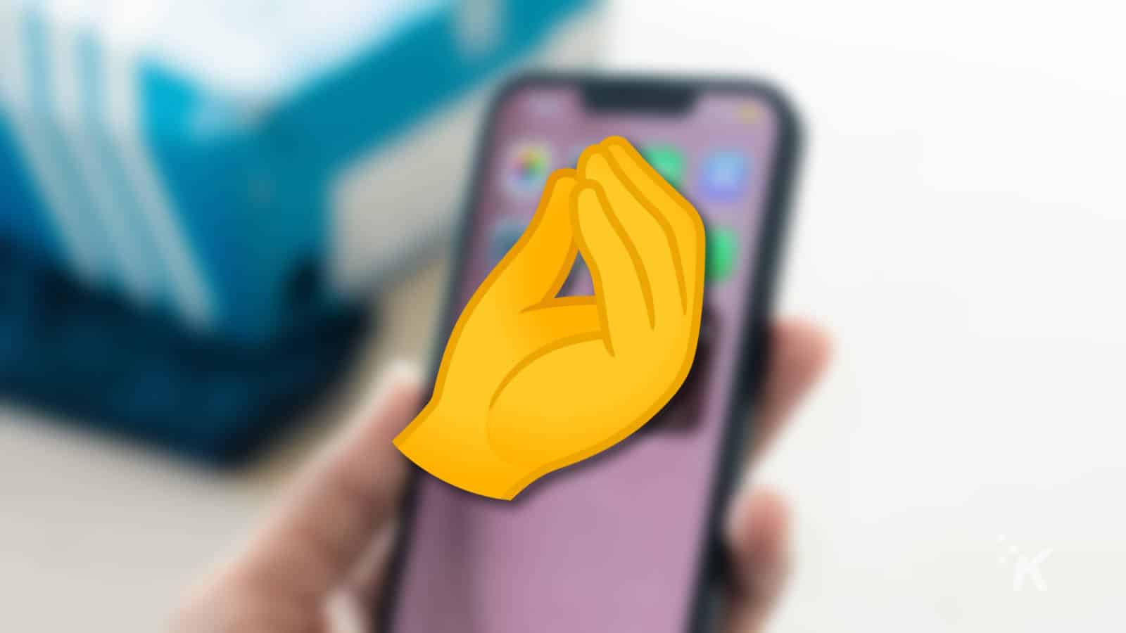 pinched hand emoji overlaid on a blurred iphone