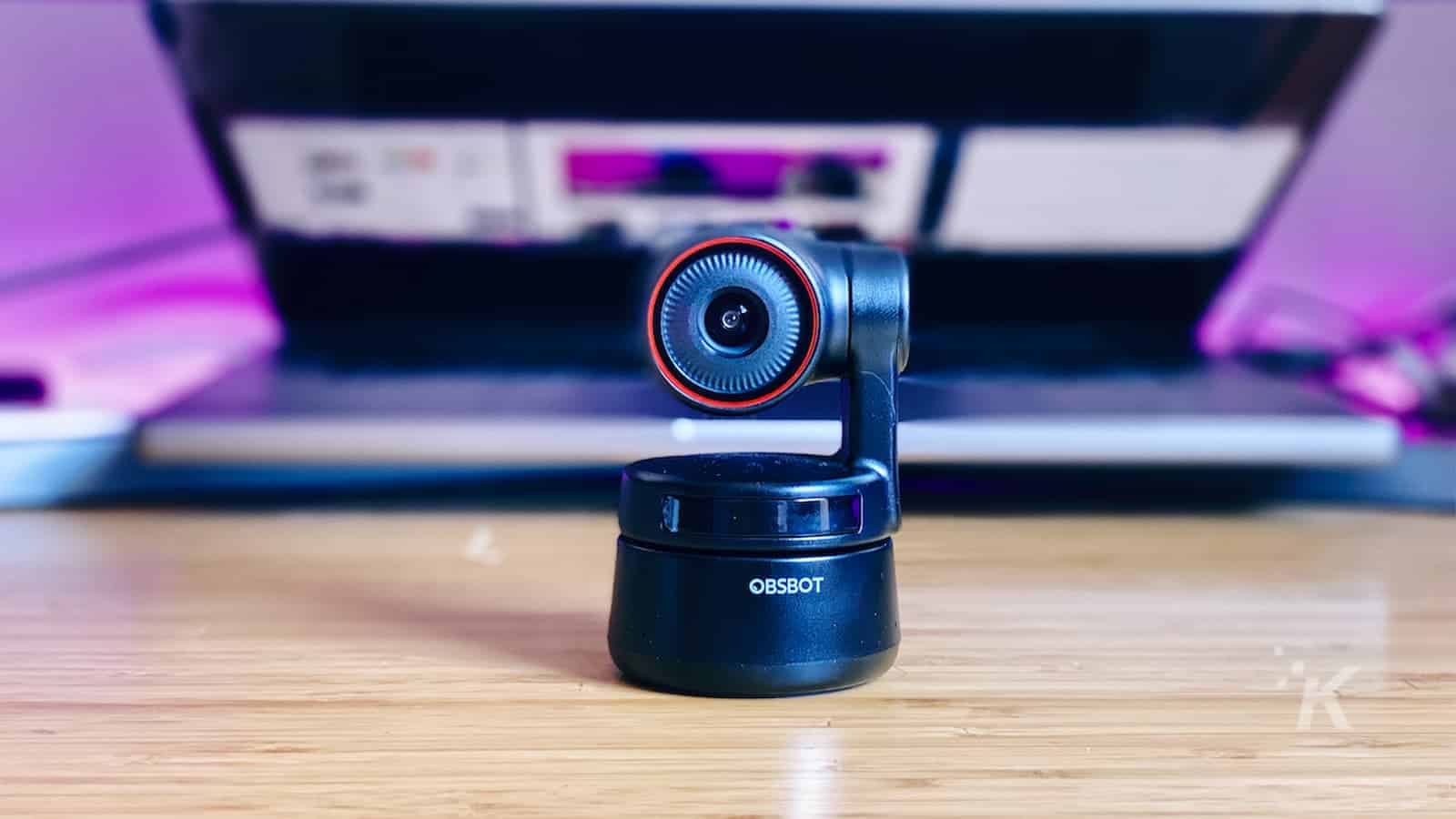 Obsbot tiny 4k webcam sitting on a desk in front of half opened laptop