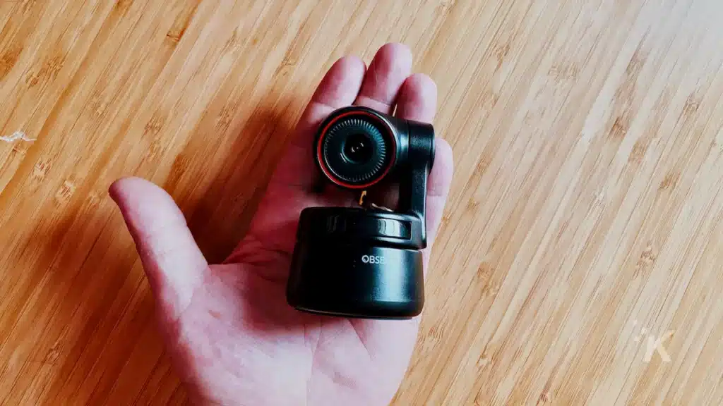 obsbot webcam in the palm of a person's hand over a wooden desk