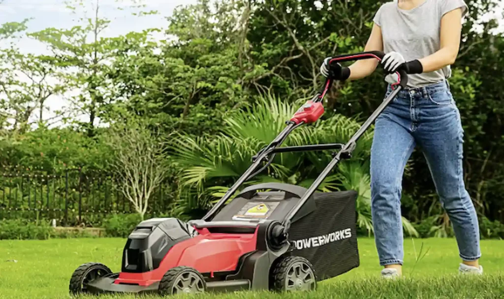 Woman mowing lawn with a cordless lawnmower