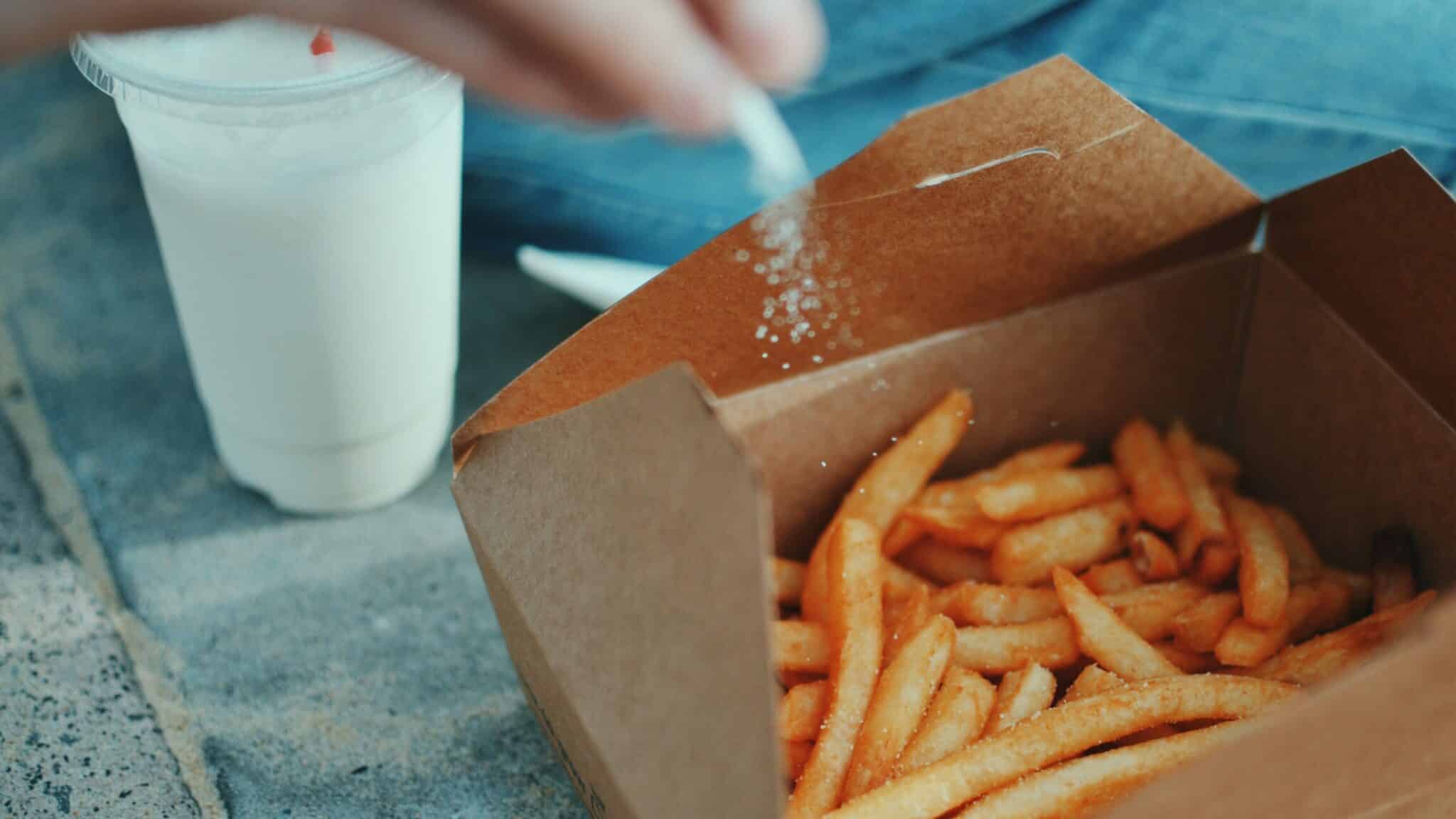 person putting salt on fries