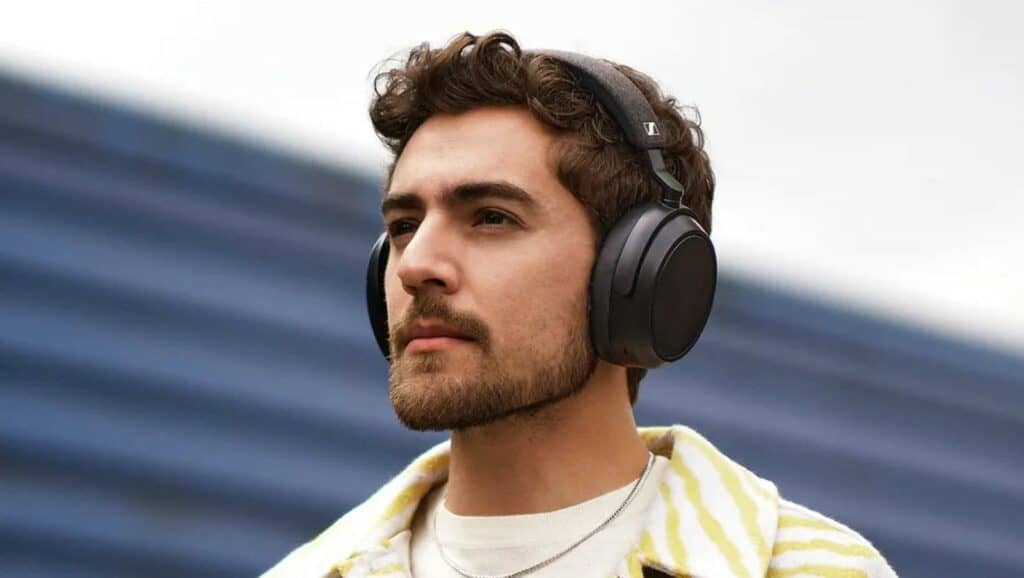 man with brown hair and white skin wearing sennheiser momentum 4 headphones