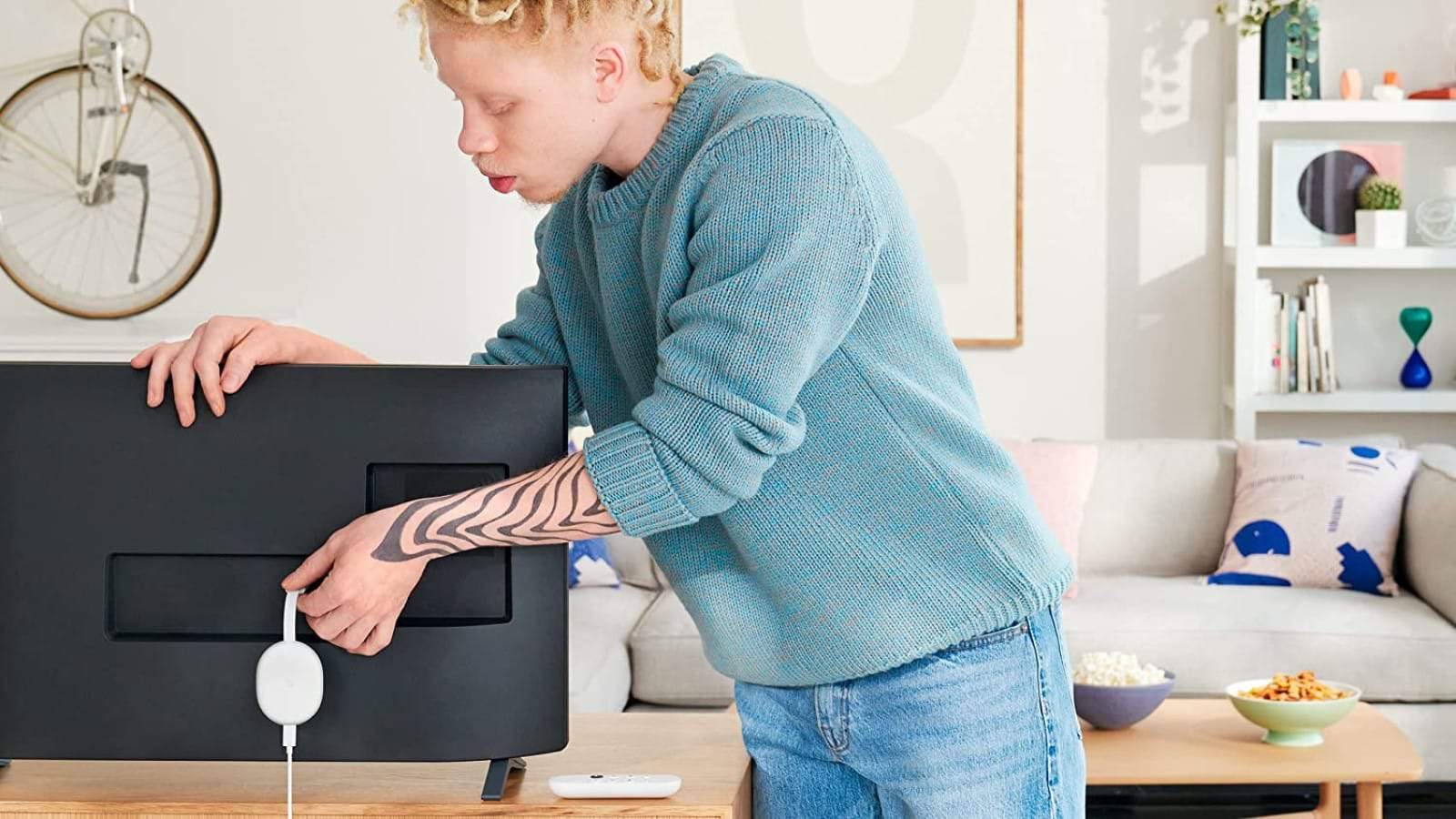 man plugging chromecast into tv