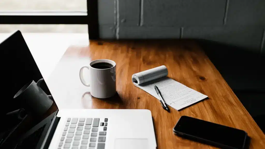 laptop coffee mug notepad phone on wooden desk