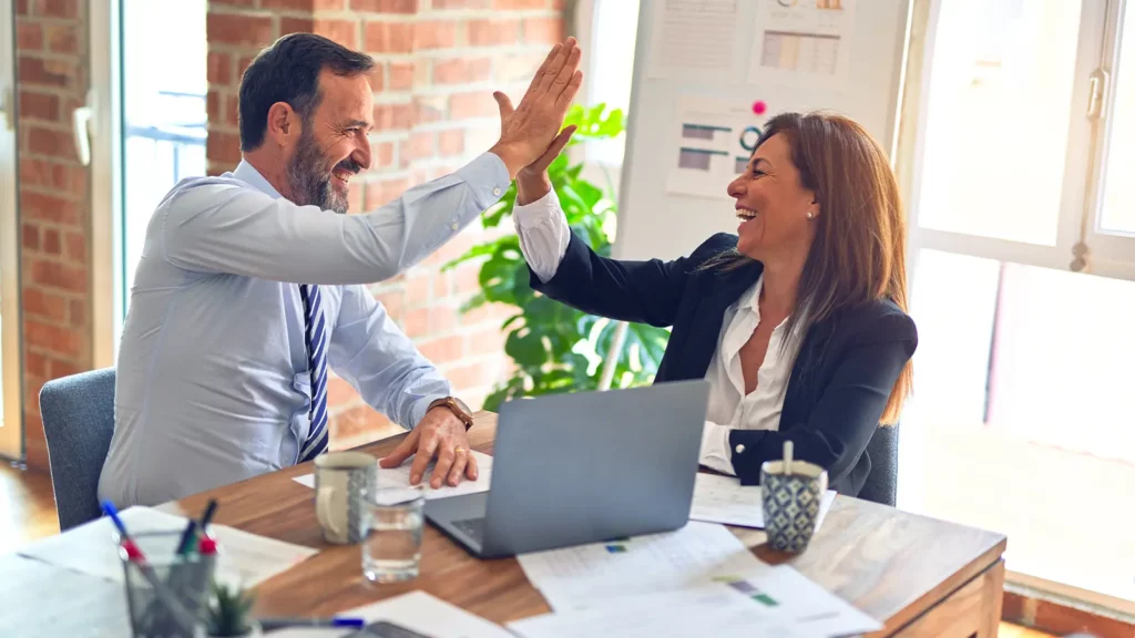 two people in an office high fiving business technology