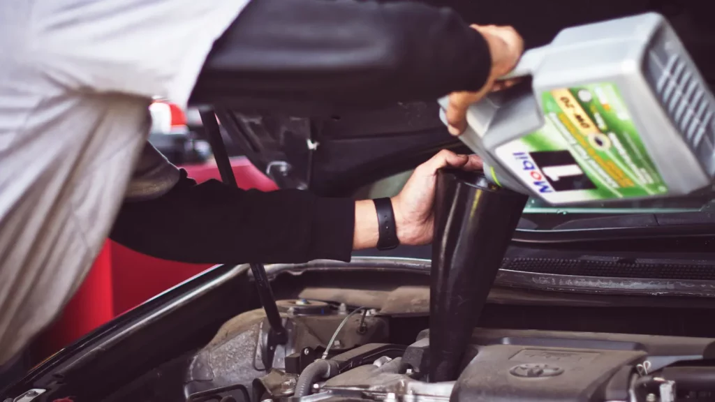 mechanic filling car with oil