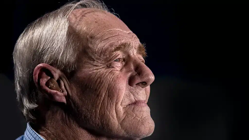 older man wearing a hearing aid side view