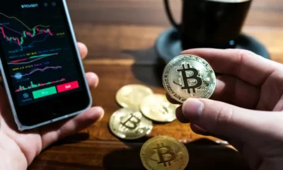 person holding a Bitcoin and a android phone