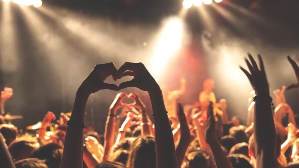 people in a concert making a heart sign