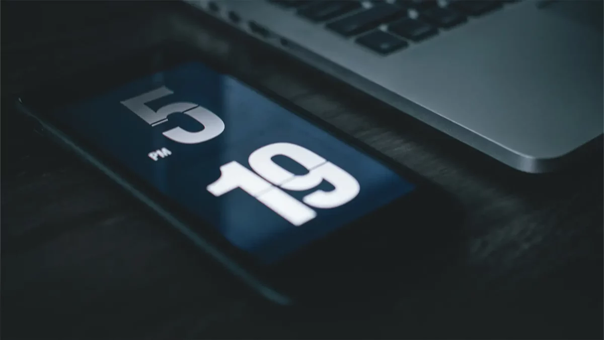 phone next to a laptop with the time 5:19 in bold white letters