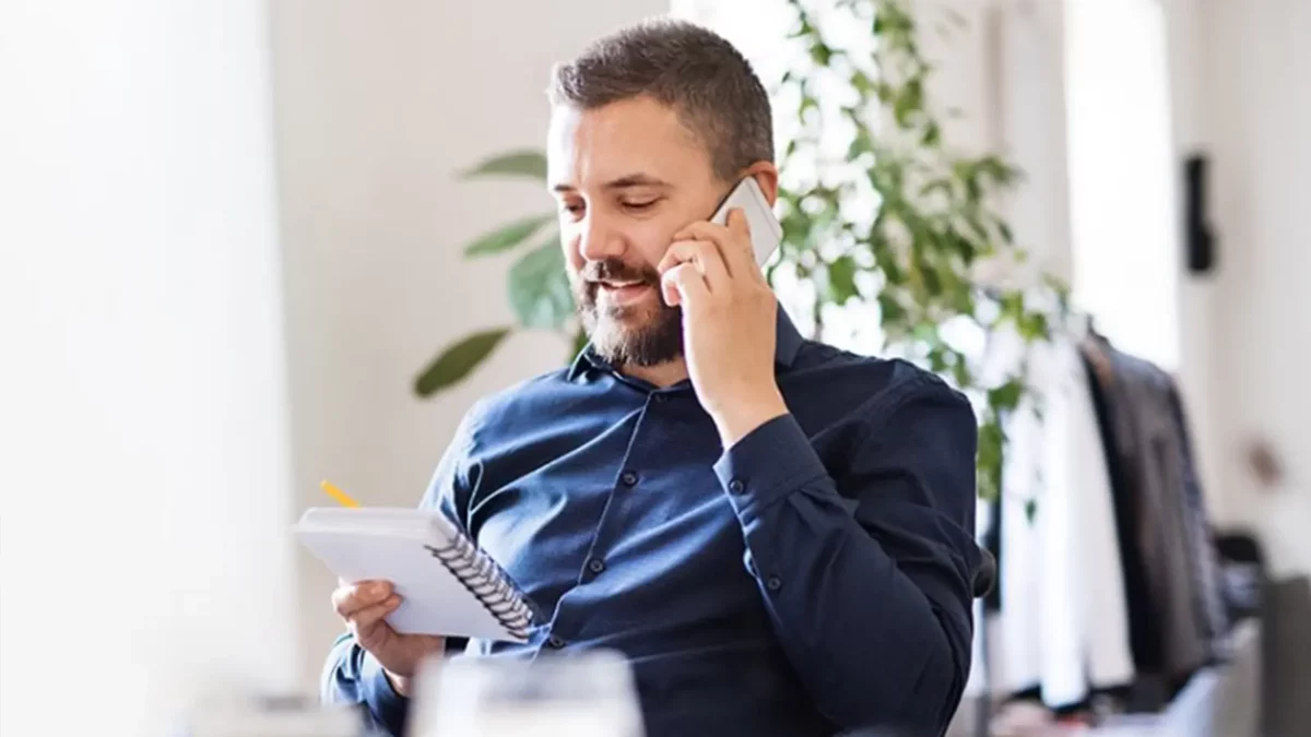 man on phone with holding a note pad