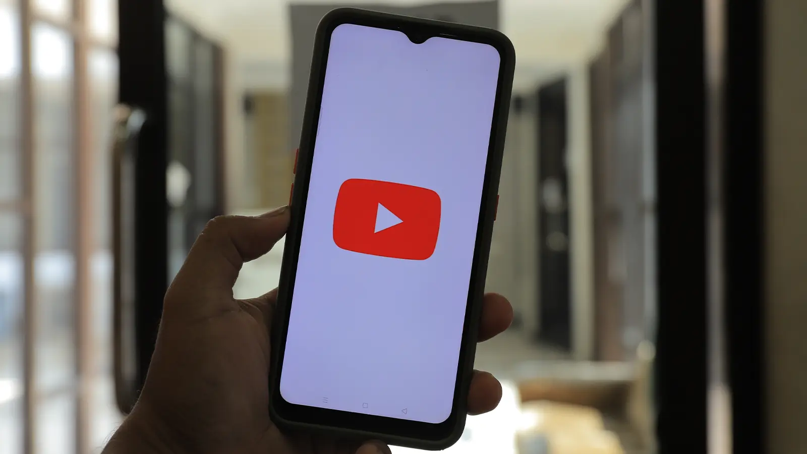 Person holding a phone with the YouTube logo on the screen.