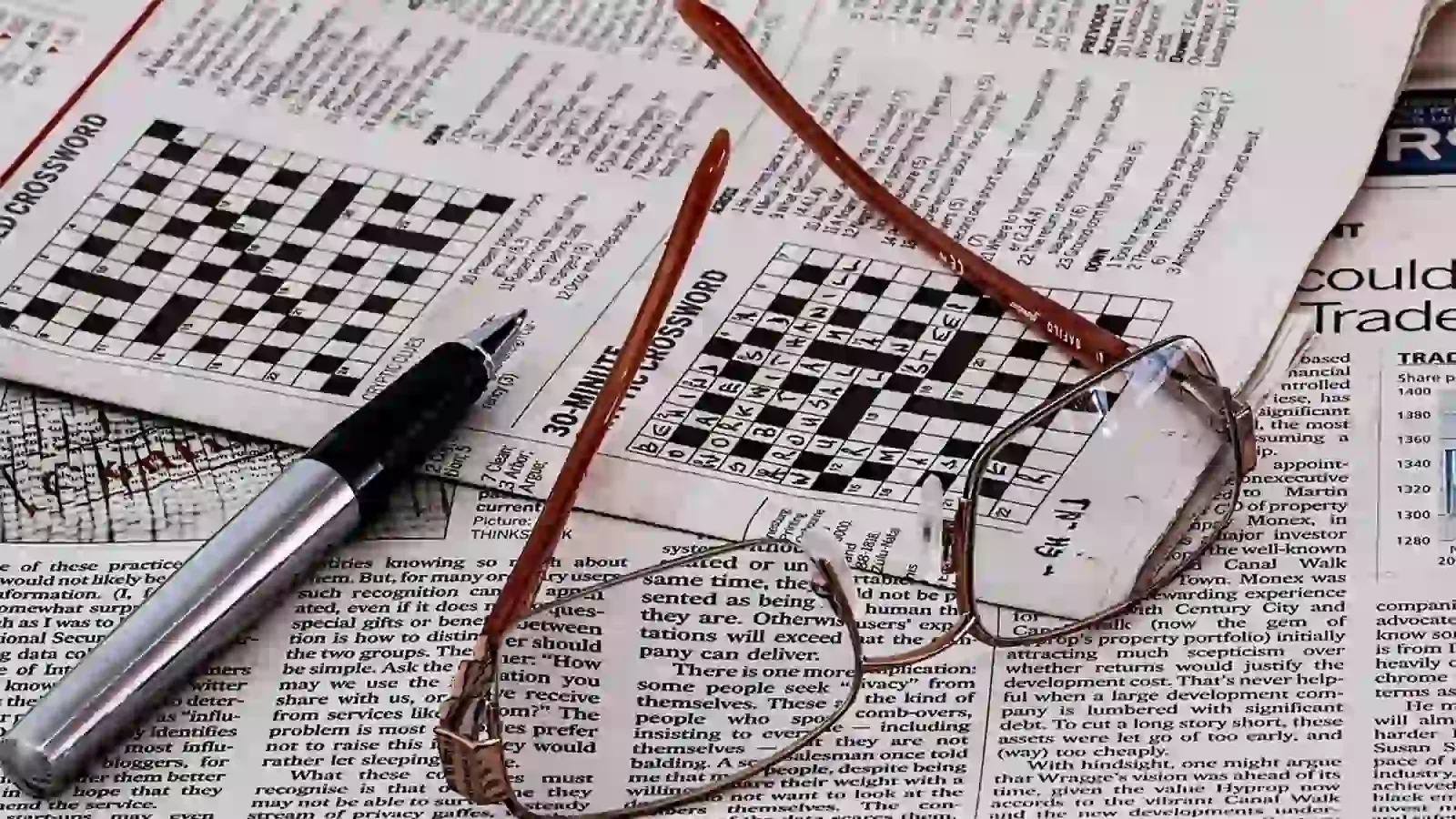 pair of glasses on top of crossword puzzles