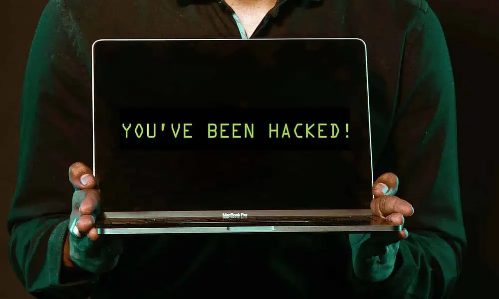 person holding laptop with the words you been hacked