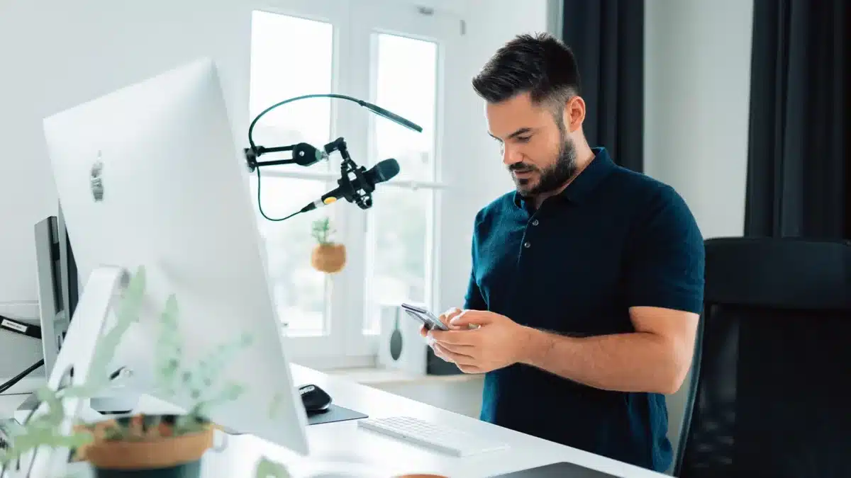 Man in front of a mic looking through his phone