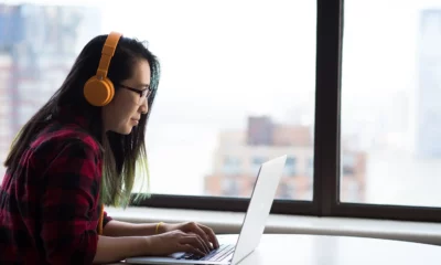 person typing on laptop with headphones on