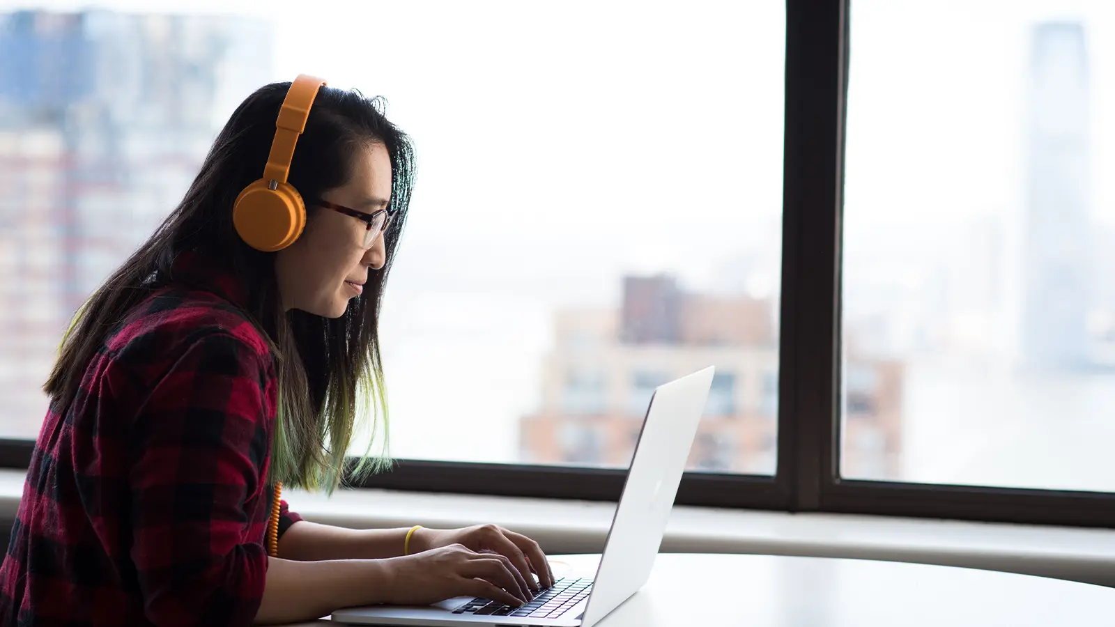 person typing on laptop with headphones on