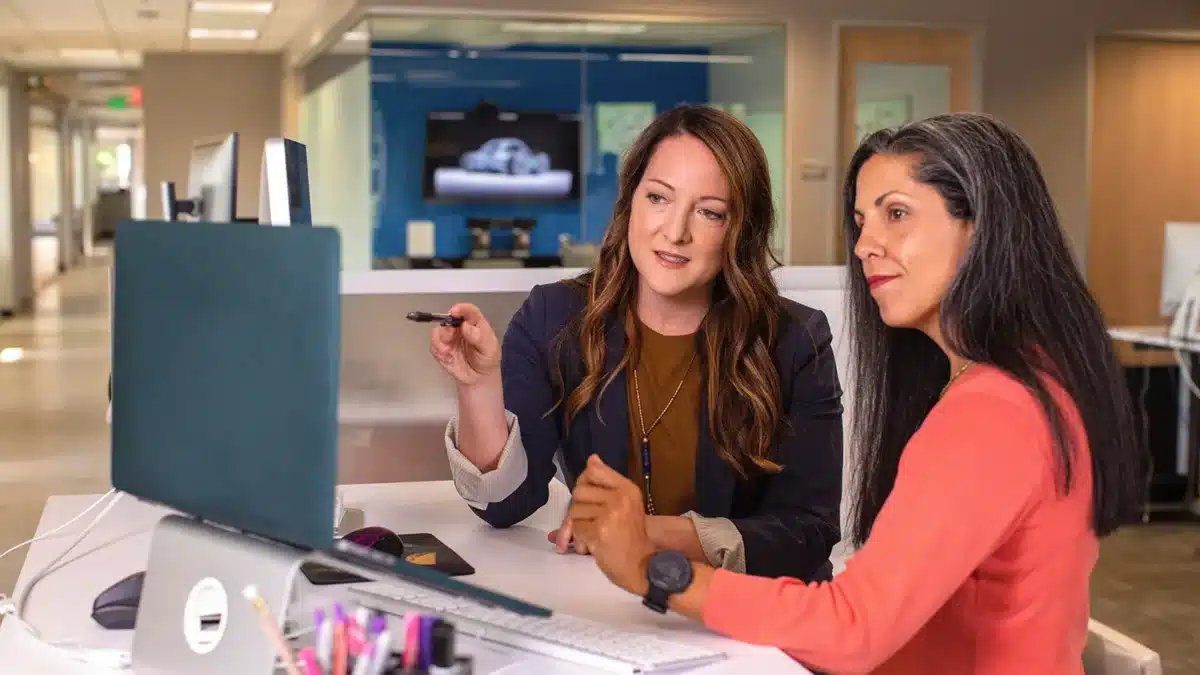 two woman looking at a computer screen in the workplace