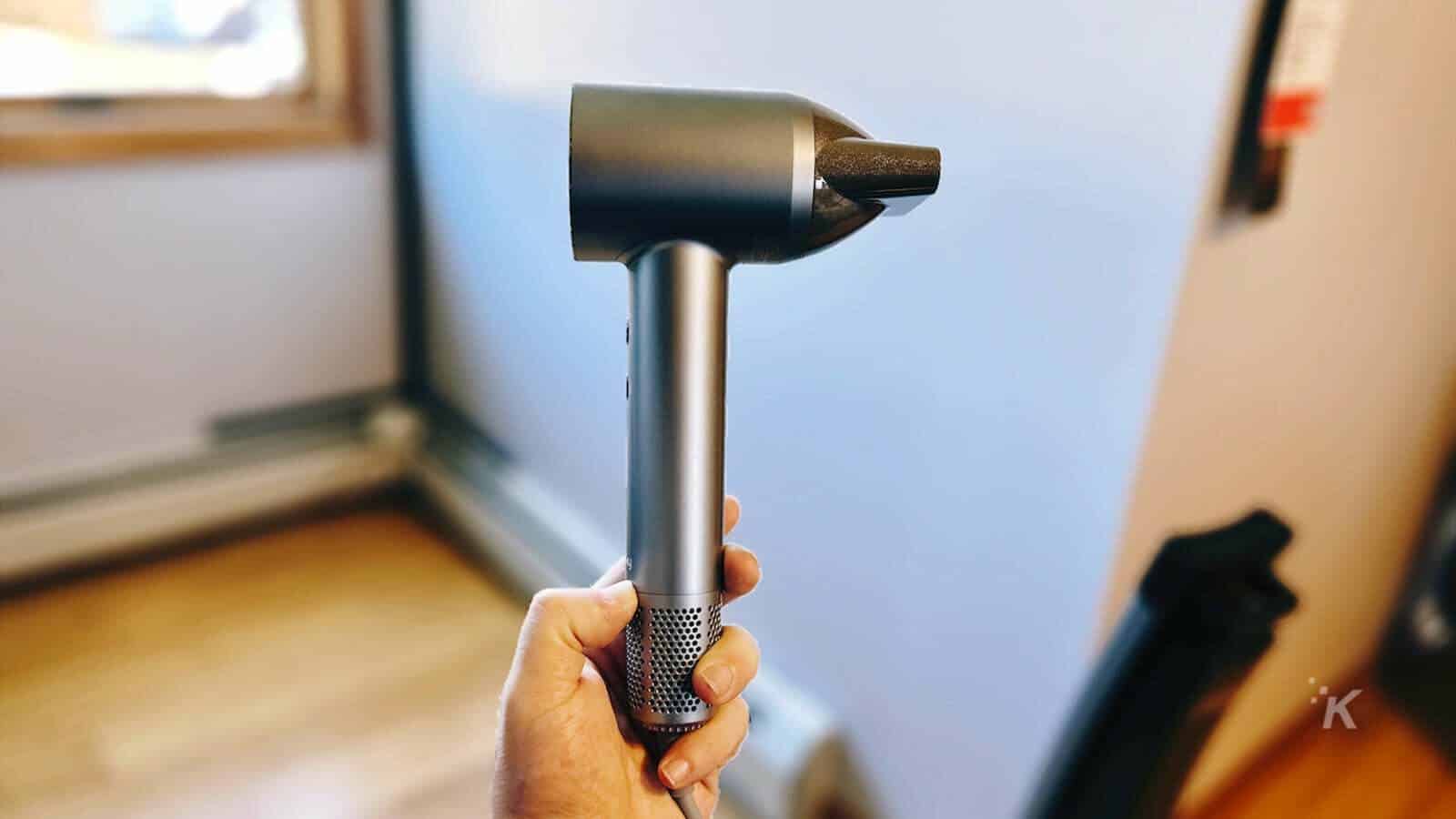 man holding a hair dryer sideways 