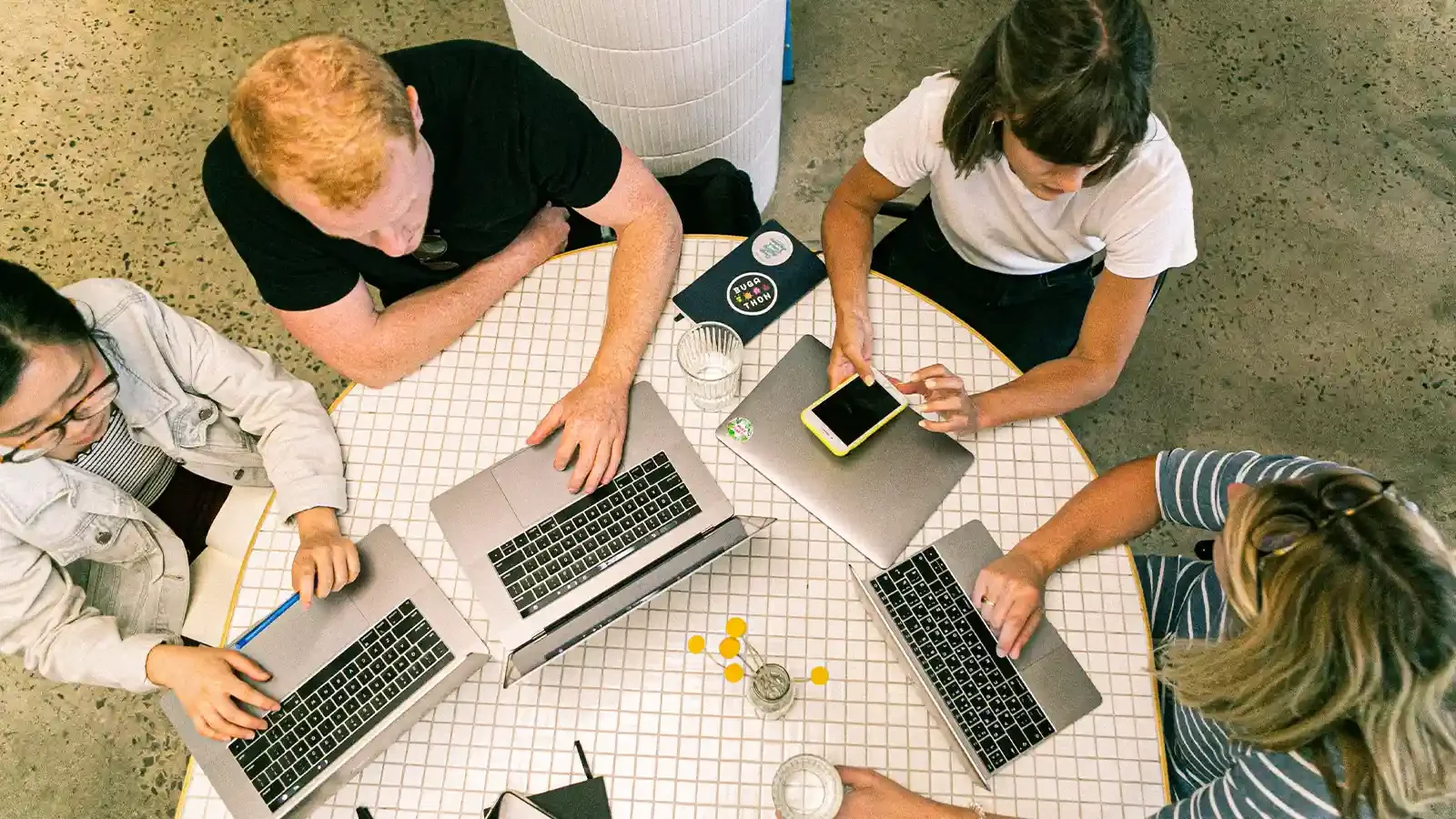 people around a table on laptops