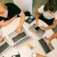 people around a table on laptops