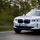 The white bmw ix3 suv electric is driving on the road.