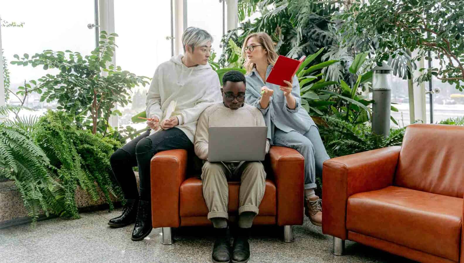 A group is using a laptop while seated on a couch.