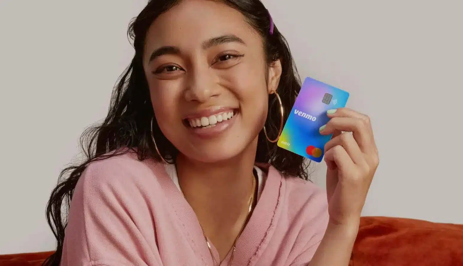 A person is holding a mobile phone and smiling while indoors.