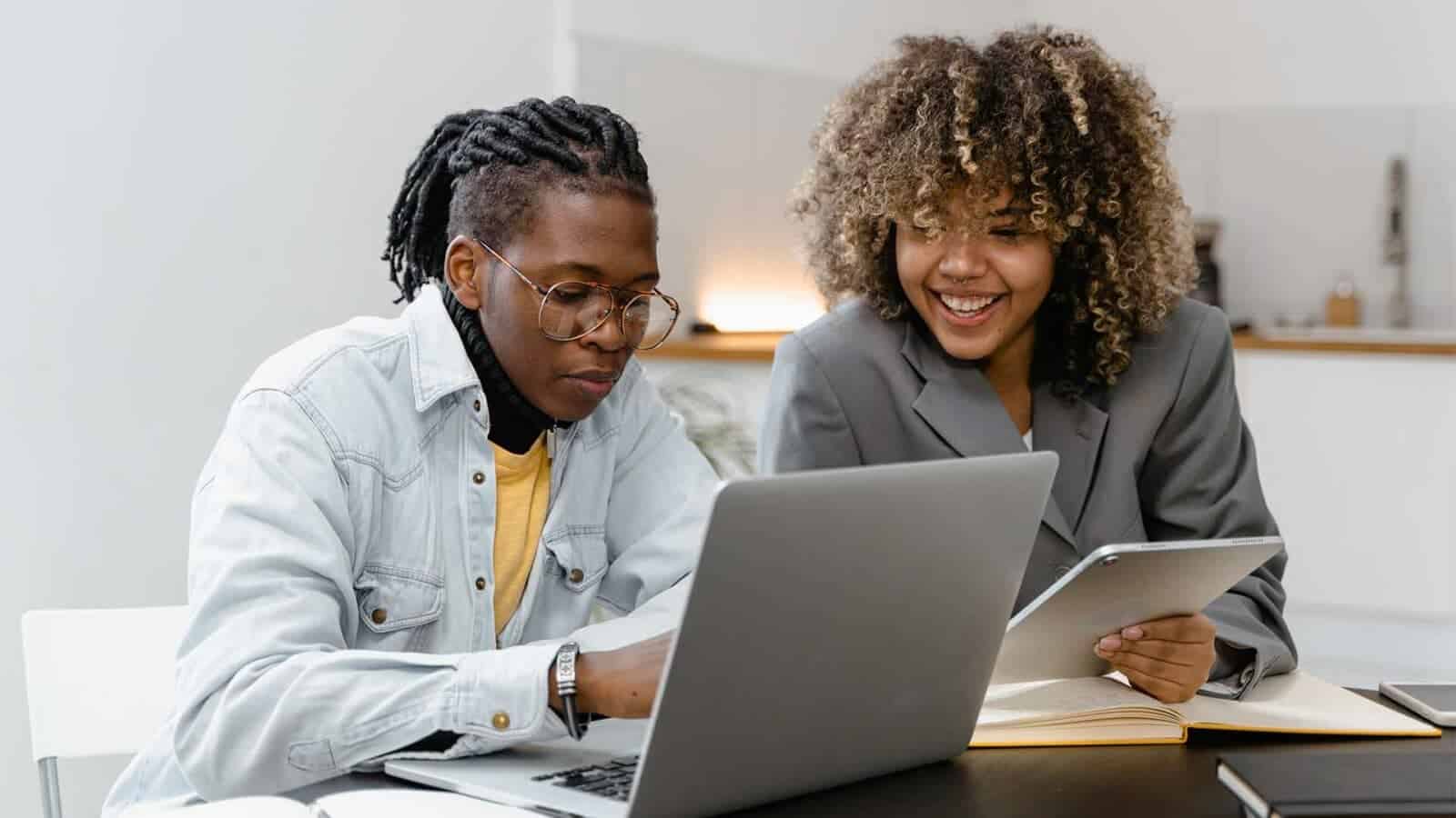 Two people are looking at a laptop.