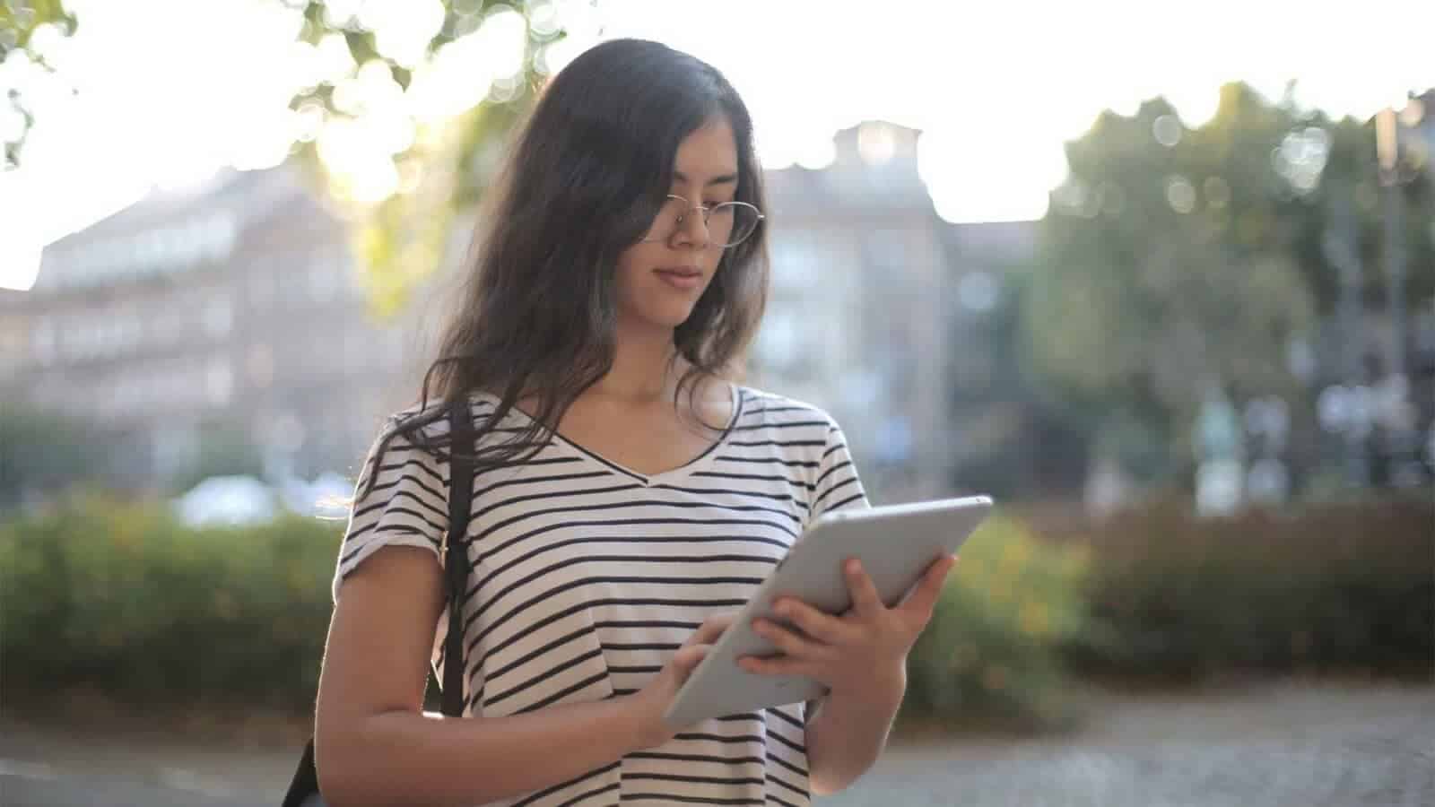 A person holds a tablet outdoors.