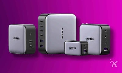 A UGREEN USB-C charger is powering a smartphone, a portable communication device, and other electronic gadgets.