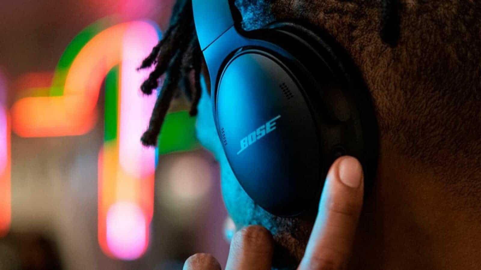 A person is wearing bose quietcomfort 45 headphones and listening to music in a brightly lit room.