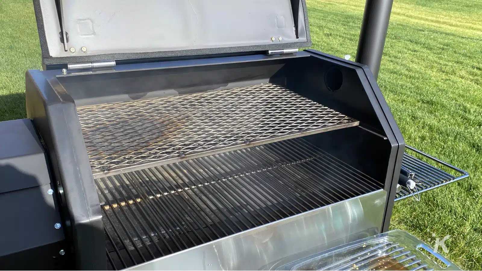 A metal pellet grill sits open and ready for cooking