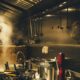 A steel locomotive is cooking in the night-lit kitchen of a factory.