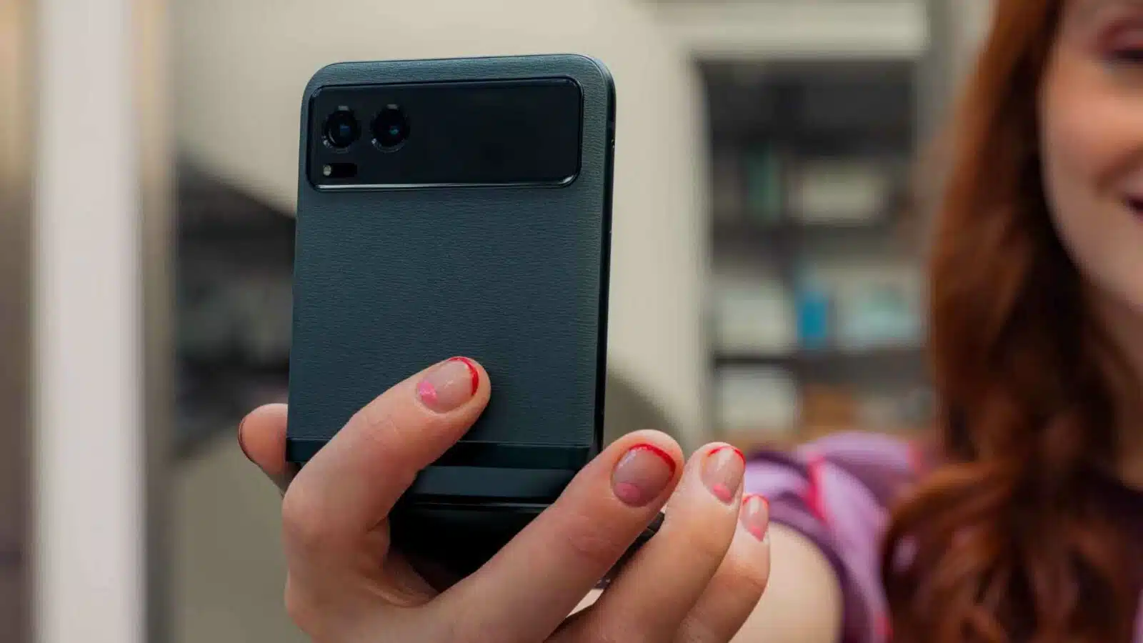 A person is holding a smartphone, a portable communications device, in their hand while their face is illuminated by the electronic device's light.