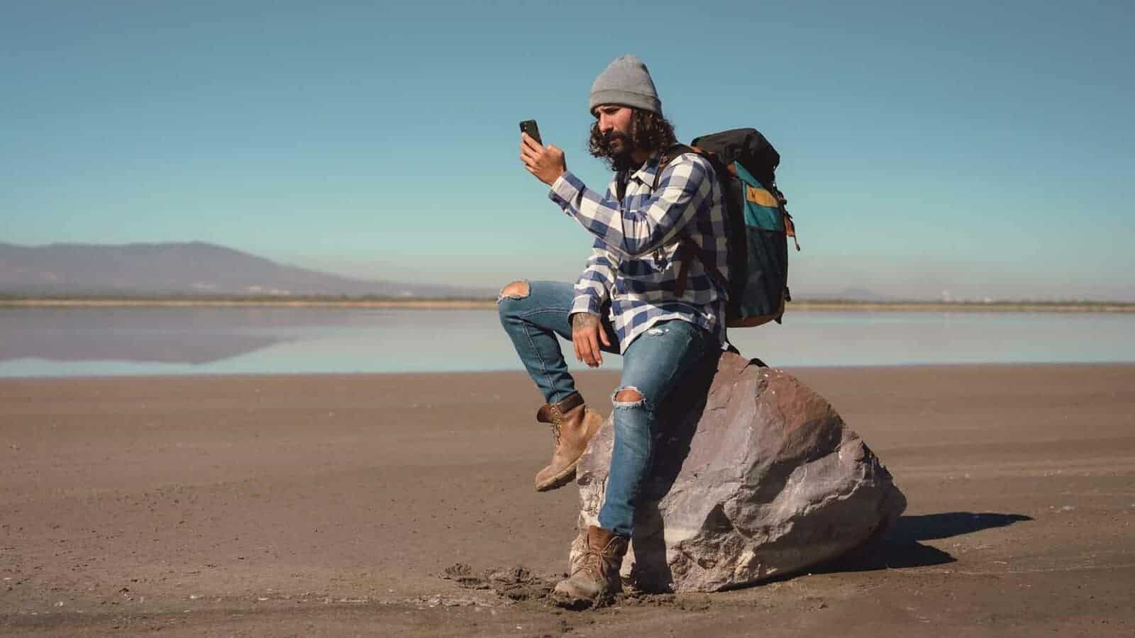 A person sits on a rock looking at his GPS receiver.