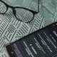 A smartphone with the ChatGPT app open lies on a patterned surface next to a pair of glasses, suggesting a work or study scenario.