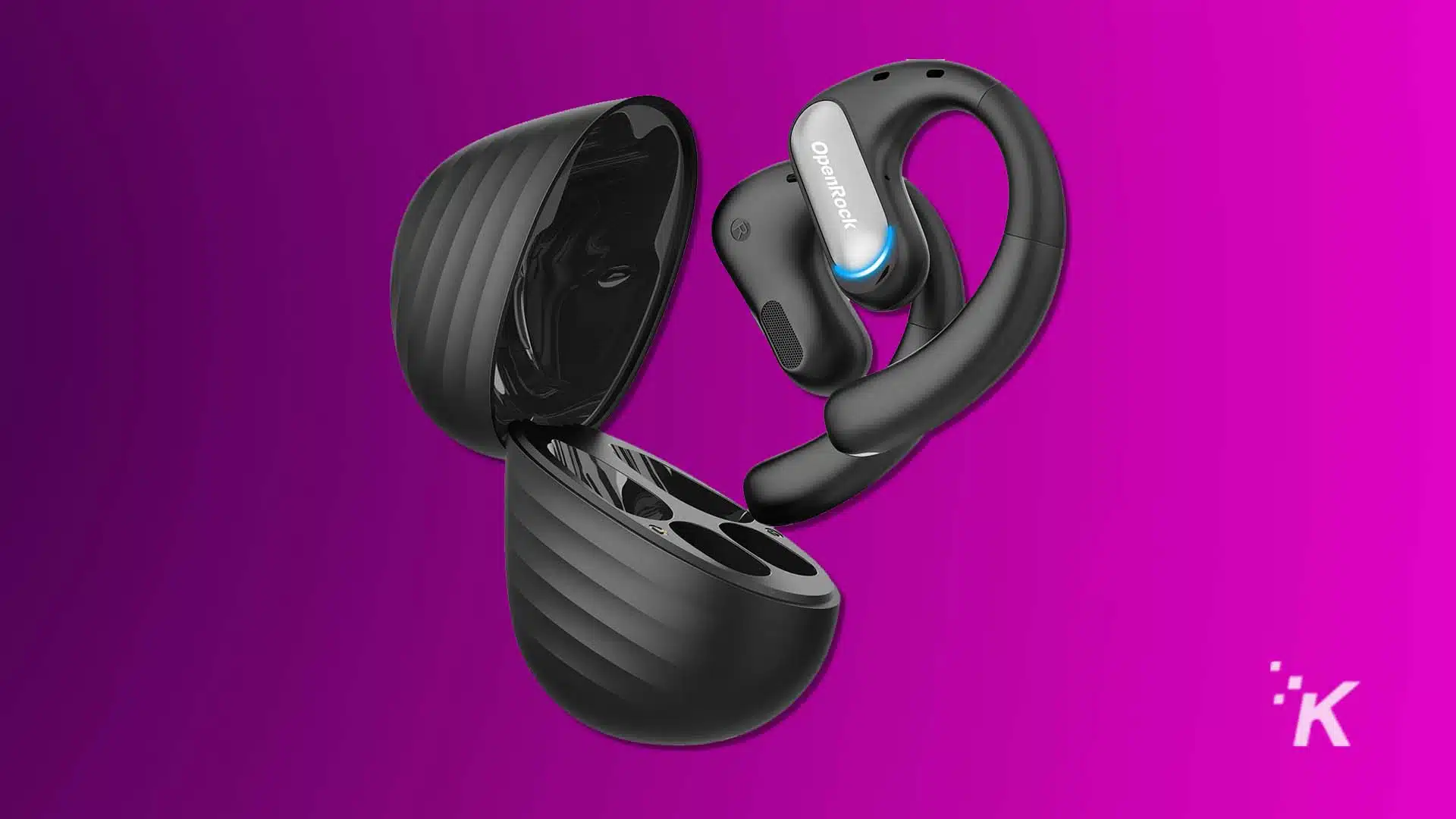 Black wireless earphones with ergonomic hooks are emerging from a matching charging case against a vibrant purple background. They appear sleek and modern. OpenRock Pro headphones