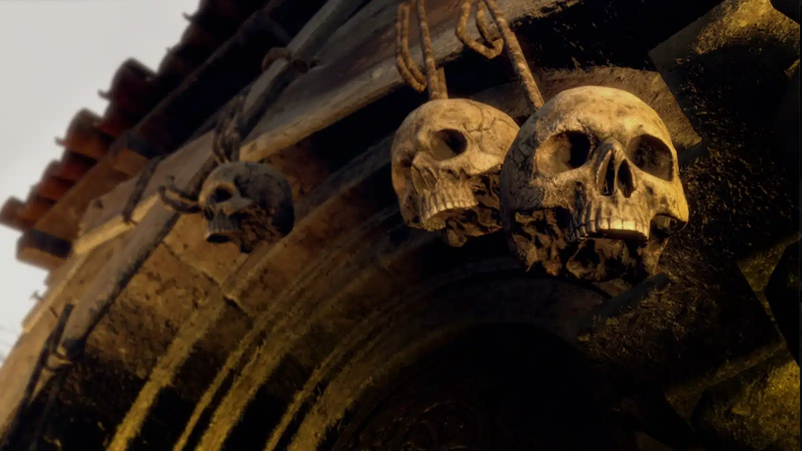 The skull sits atop a tall outdoor building against a bright blue sky.