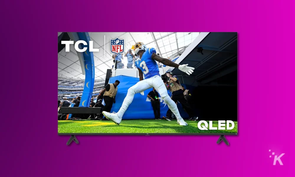 An image displays a large tcl qled television showcasing an american football player in a blue jersey diving towards a goal line during an nfl game.