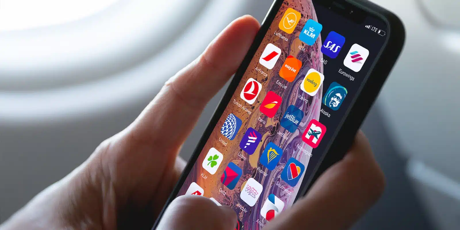 hands holding a smartphone with airline apps displayed on it