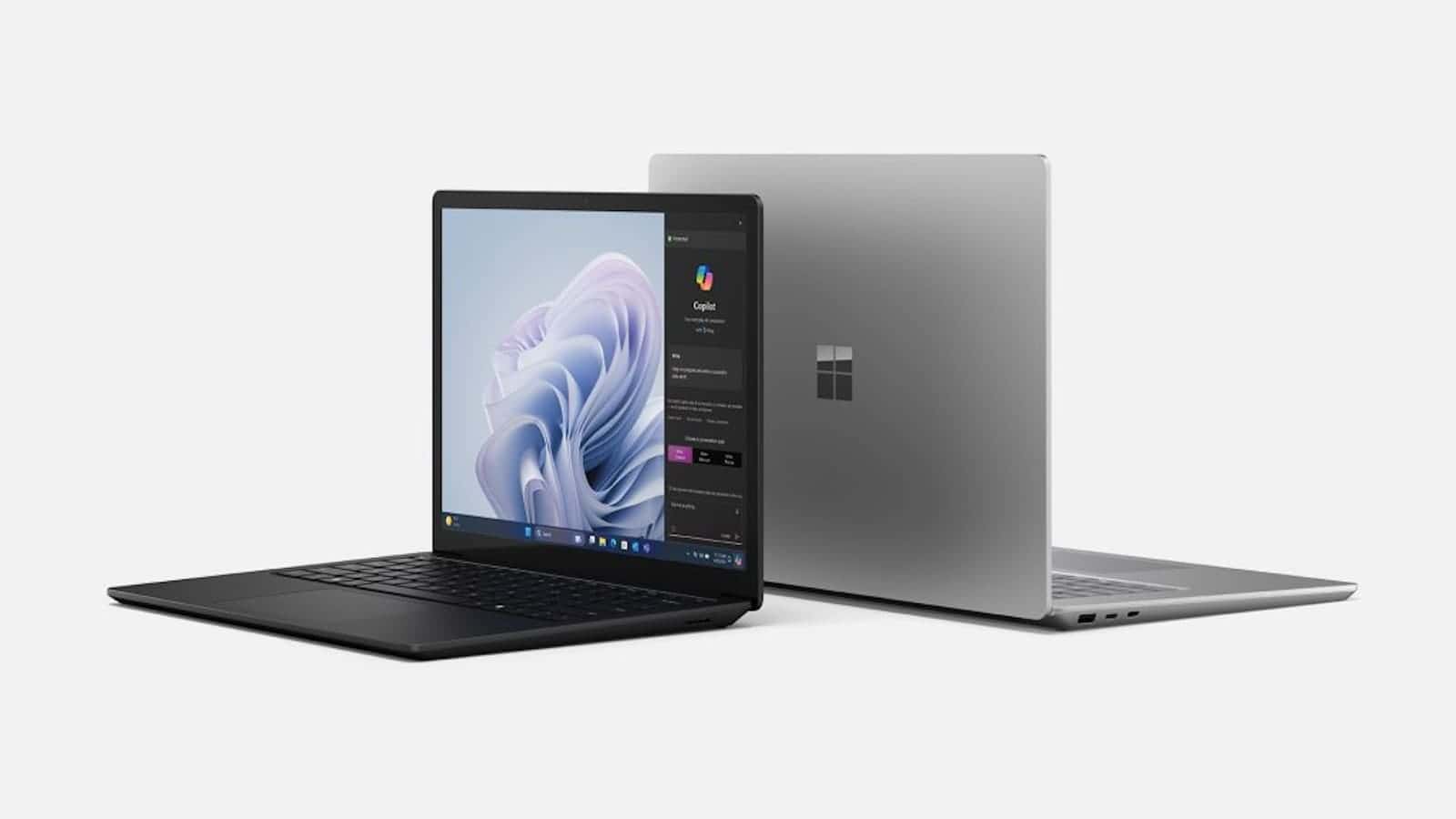 Two laptops placed against a white background, one opened showing a desktop screen with wallpaper and taskbar visible, and the other closed showing the logo on its lid.