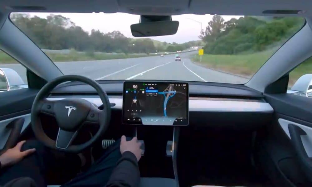 Interior view of a car with hands-free driving on the highway, displaying a large central touchscreen with navigation map and vehicle status.