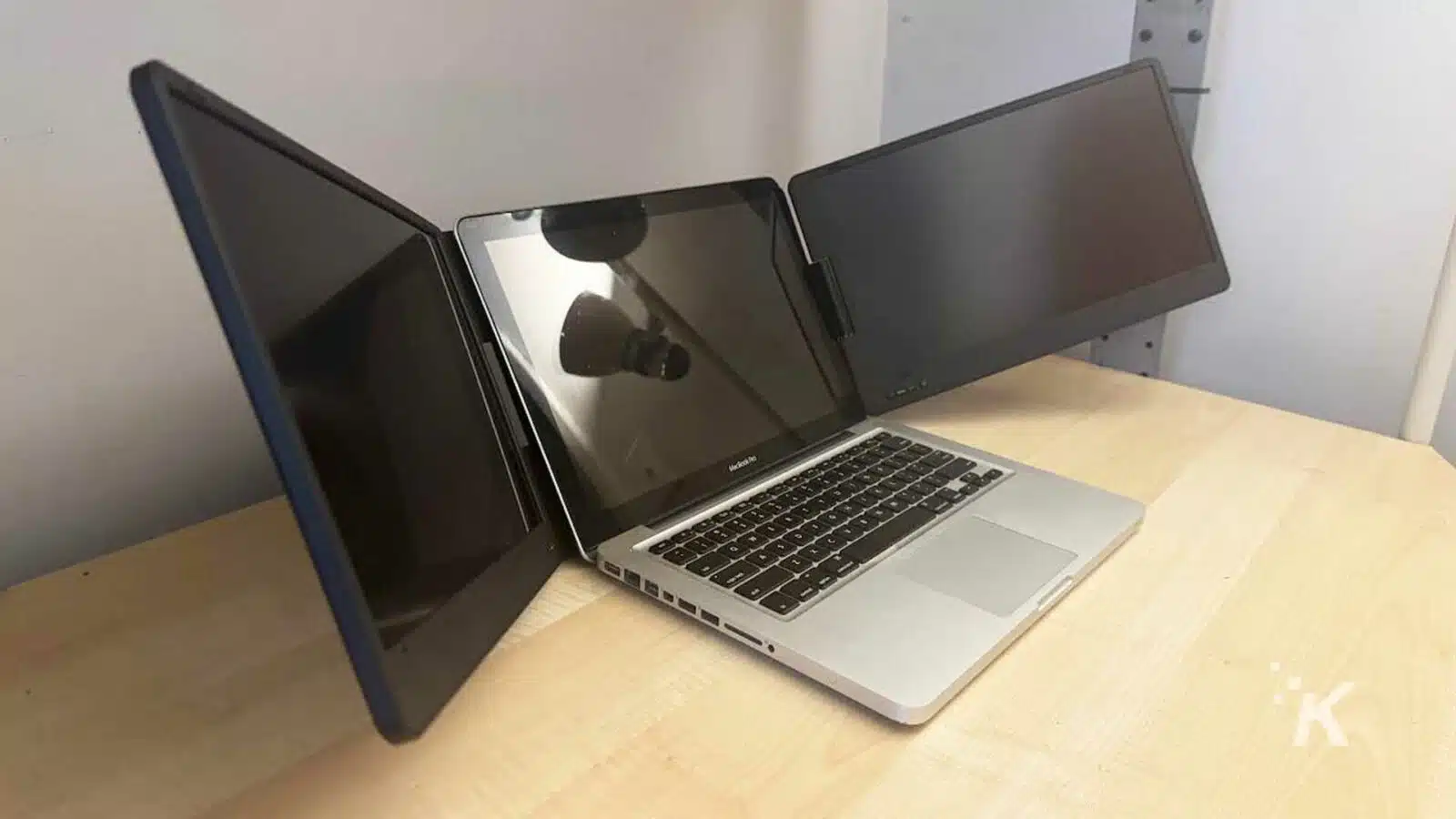 the QQH triple laptop screen extender with a laptop on a desk.